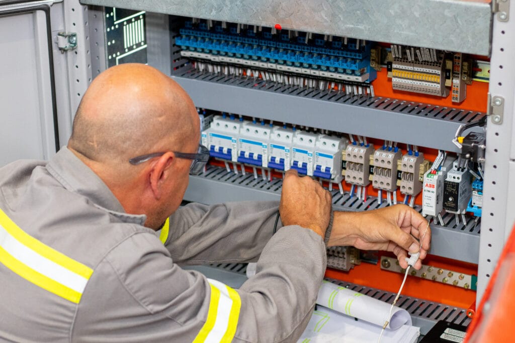 Homem ajustando Painéis Elétricos.